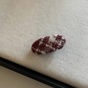 Detail of red and white knitted oval hair clip showing vintage winter wool texture