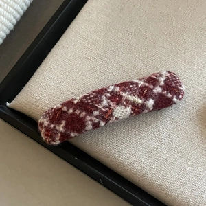 Detail of red and white tweed fabric texture on a long vintage hair clip accessory
