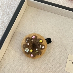 Gros plan sur une pince à cheveux donut en feutre faite main avec des perles colorées