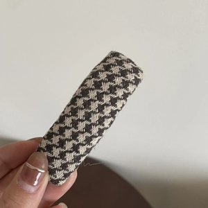 Close-up of a vintage houndstooth fabric hair clip held by hand with elegant texture