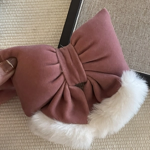 Close-up of a velvet pink bow hair clip with white faux fur trim and soft winter textures