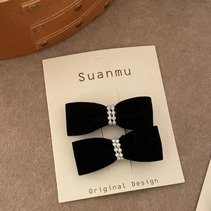 Set of two black velvet bow hair clips with elegant pearl beads on a display card