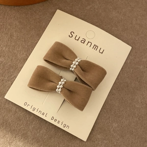 Brown velvet bow hair clips set with elegant white pearls on a display card