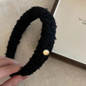 Detail of black wide headband with fuzzy lamb wool texture and golden metal button