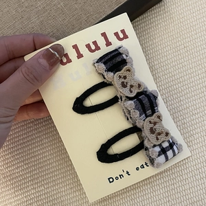 Détail de barrettes à carreaux avec ours brodés sur un emballage en carton de qualité