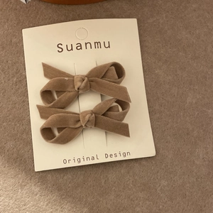 Detail shot of two vintage brown velvet bow hair clips on a white presentation card