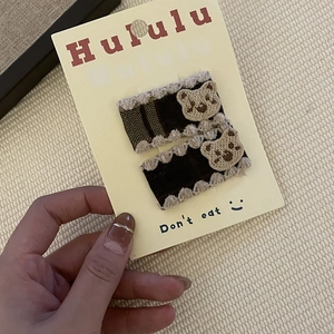 Détail de barrettes en velours marron avec dentelle beige et broderie d'ourson mignon