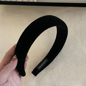 Detail of handmade black velvet headband with stitched brand label on inner side