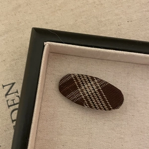 Close-up of fabric hair clip with vintage plaid check pattern in a jewelry tray