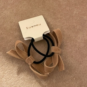 Detail of two-piece brown velvet bow hair ties on a textured display card