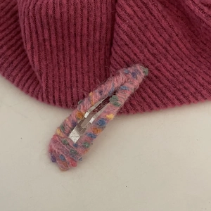 Handgemaakte regenboog gebreide haarspeld met kleurrijke woltextuur en een metalen BB-clip
