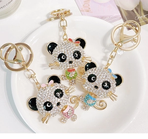 Detailed macro view of three sparkling rhinestone panda keychains on a white porcelain tray