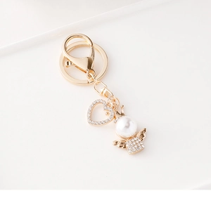 Close-up of golden angel and heart pendant keychain with sparkling rhinestones and pearls