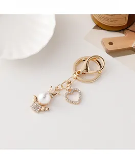 Close-up of golden angel keychain with pearl wings and sparkling rhinestone heart charm