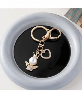 Detailed macro view of golden angel pearl charm and rhinestone heart on keychain