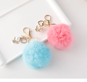 Dettaglio di portachiavi angelo in peluche rosa e blu con cuore di cristallo e perle