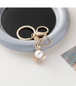 Detailed macro shot of an angel keychain with pearl head, golden crown, and heart charm