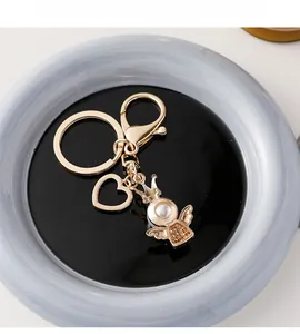 Detail of golden baby baptism keychain featuring an angel charm and hollow heart pendant