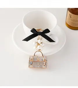 Détail du porte-clés sac à main avec nœud noir, perles blanches et pendentif en cristal