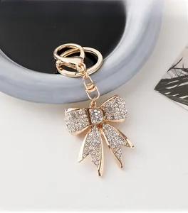 Détail d'un porte-clés nœud doré avec pendentif lettre D et strass brillants