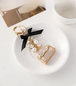 Détail d'un porte-clés de luxe avec nœud en soie, perles et breloque de sac à main chic