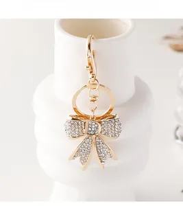 Détails d'un porte-clés nœud doré orné de strass brillants sur un vase en céramique blanc