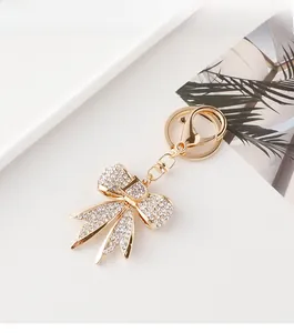 Détail d'un porte-clés nœud en strass avec breloque lettre D dorée et fermoir mousqueton