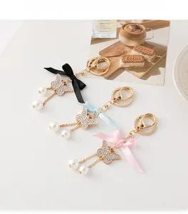 Détail d'un porte-clé papillon élégant avec strass, perles et un nœud en satin