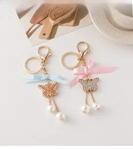Détail de porte-clés papillon avec perles et rubans de soie en bleu et rose pastel