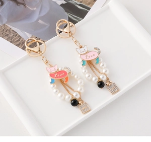 Detail of enamel cat keychain with pearls and rhinestone perfume bottle pendant