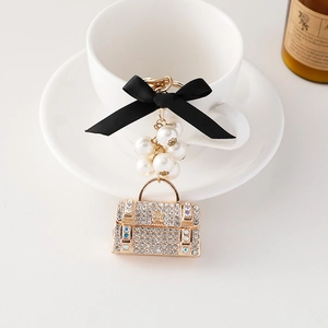 Porte-clés sac à main élégant avec strass, nœud noir et perles sur une tasse blanche