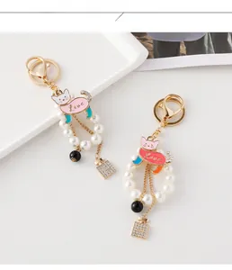 Detail of cat pearl keychain featuring Love inscription and sparkling perfume bottle charm