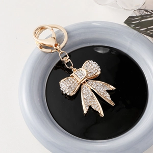 Porte-clés nœud en cristal étincelant avec pendentif lettre D doré sur plateau céramique
