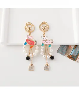Detailed view of cat charm keychain with pearls and rhinestone perfume bottle pendant