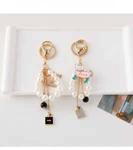 Detailed view of handmade pearl cat keychains with gold hardware and enamel perfume charms