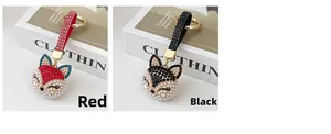 Close-up of red and black fox keychains with crystals, pearls, and woven leather straps