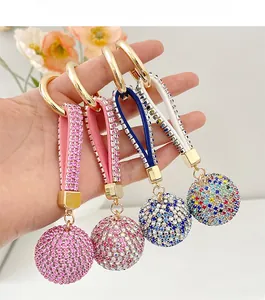 Detailed macro view of four colorful rhinestone ball keychains with gold metal rings