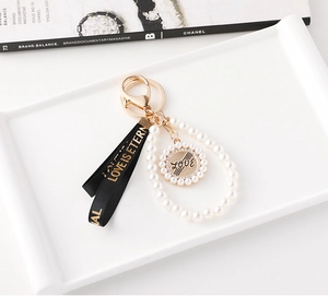 Vue détaillée du porte-clés en perles avec disque Love et ruban noir élégant de style