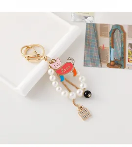 Detailed view of cat pearl keychain with red enamel cat and crystal perfume bottle charm