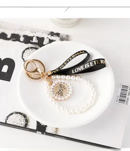 Détails de la chaîne en perles et du ruban LOVE IS ETERNAL sur un porte-clés de luxe