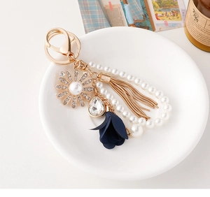 Detailed shot of pearl beaded sunflower keychain with tassel and crystal in ceramic bowl
