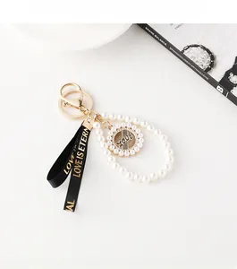 Détail du porte-clés perles de luxe avec breloque LOVE dorée et ruban satiné noir