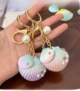 Gros plan d'un porte-clés coquillage dégradé avec perle blanche et fermoir doré