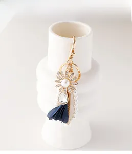 Detail of floral keychain with daisy rhinestone, pearl tassel and blue fabric petals