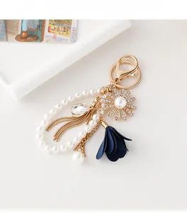Detailed close-up of pearl bead keychain with sunflower charm and golden tassel