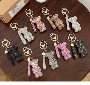 Detailed view of rhinestone bear keychains in nine vibrant colors on a wooden table