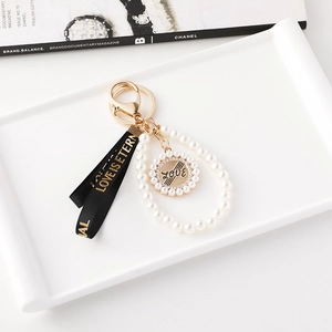 Porte-clés perles élégant avec pendentif Love et ruban noir sur un plateau blanc
