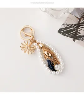 Detail of elegant pearl keychain with gold sunflower charm and navy blue ribbon