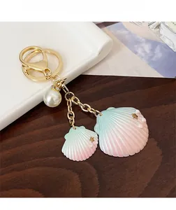 Détail d'un porte-clés en coquillage dégradé avec perle blanche et étoiles dorées