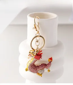 Détail d'un porte-clés dragon en cristal rose accroché sur un vase en céramique blanche